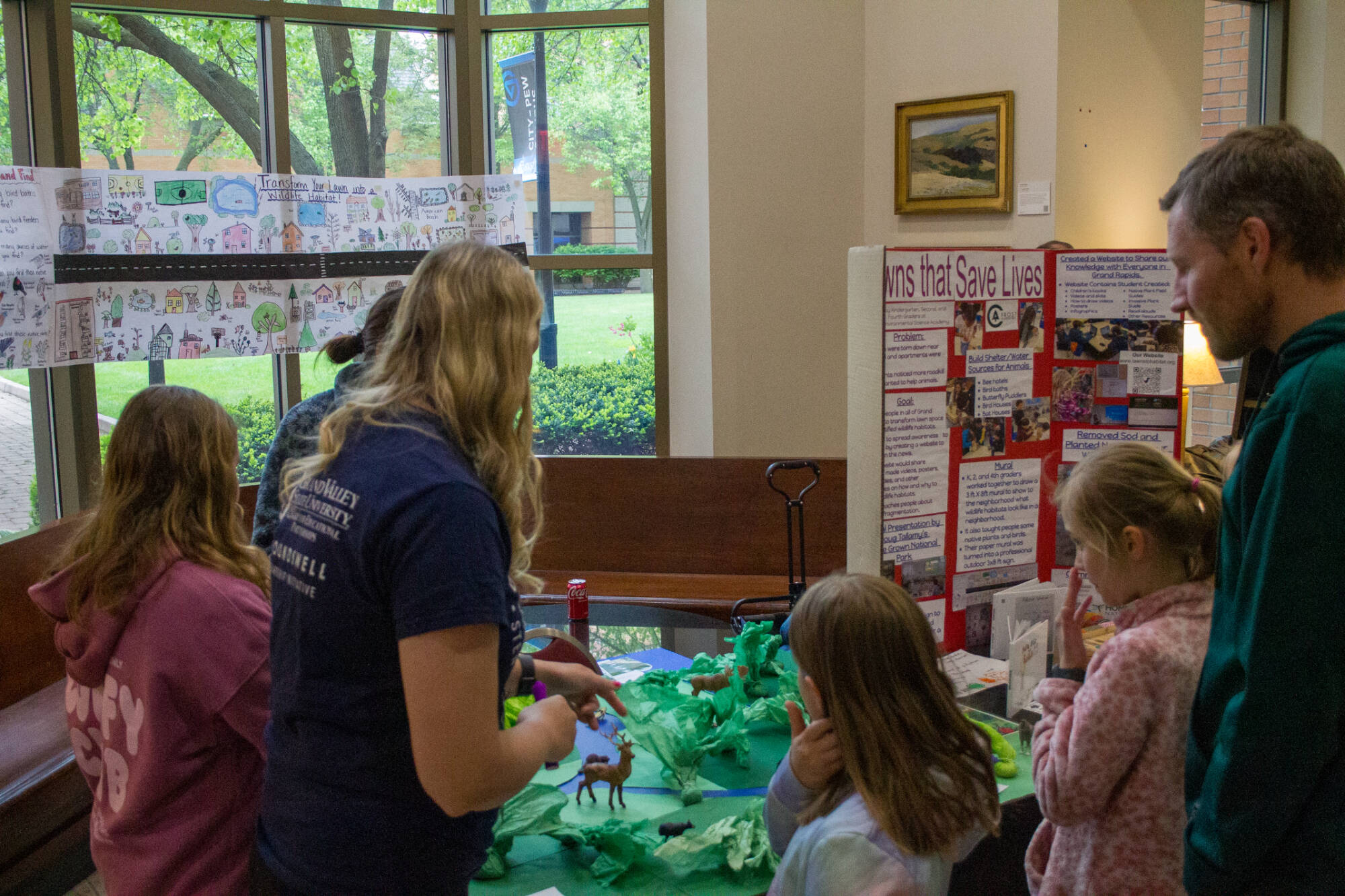 Group of students and adults looking at a Groundswell Student Showcase display